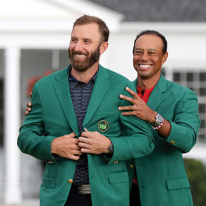 Last year's Masters champion Tiger Woods (right) presents Dustin Johnson his first green jacket after winning the Masters Tournament Sunday, Nov. 15, 2020 at Augusta National in Augusta, Georgia. (Curtis Compton/Atlanta Journal-Constitution/TNS)